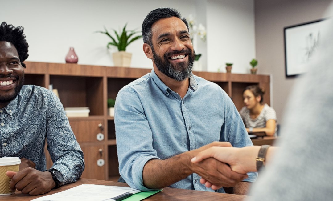 A smiling business owner shaking hands across a table